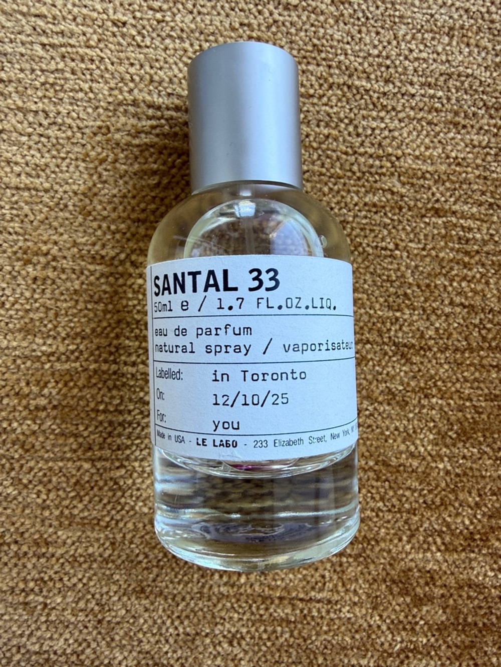 Le Labo Santal 33 - Clear Glass Bottle with Silver Cap on Tan Surface